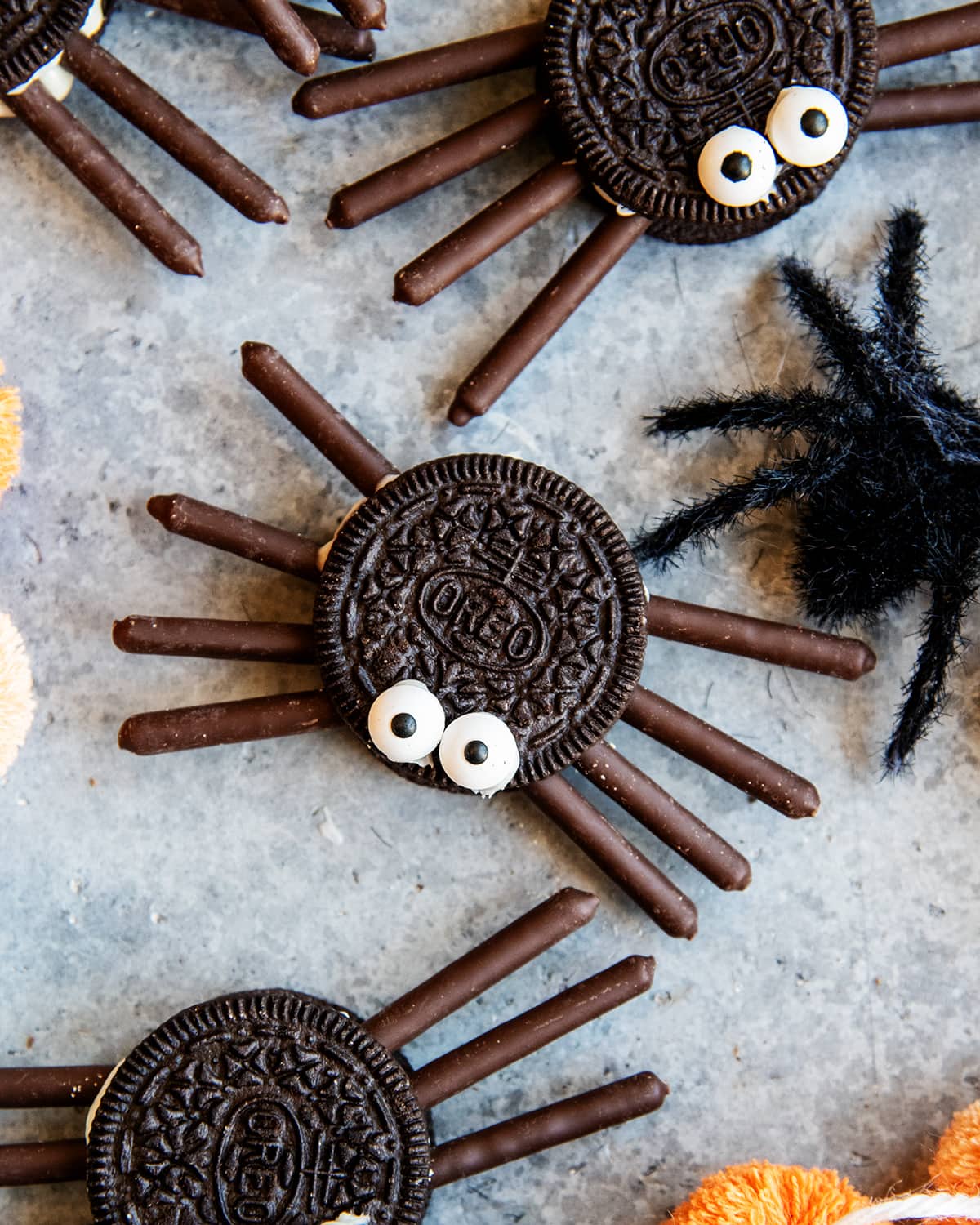 An Oreo spider with two candy eyes on top, and chocolate pocky sticks for the legs.
