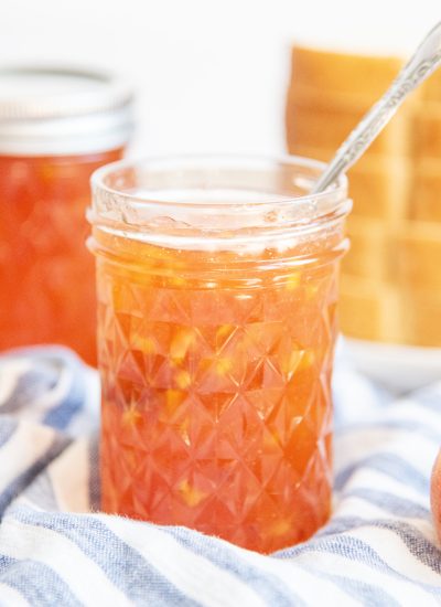 A jar of peach freezer with a spoon it it.