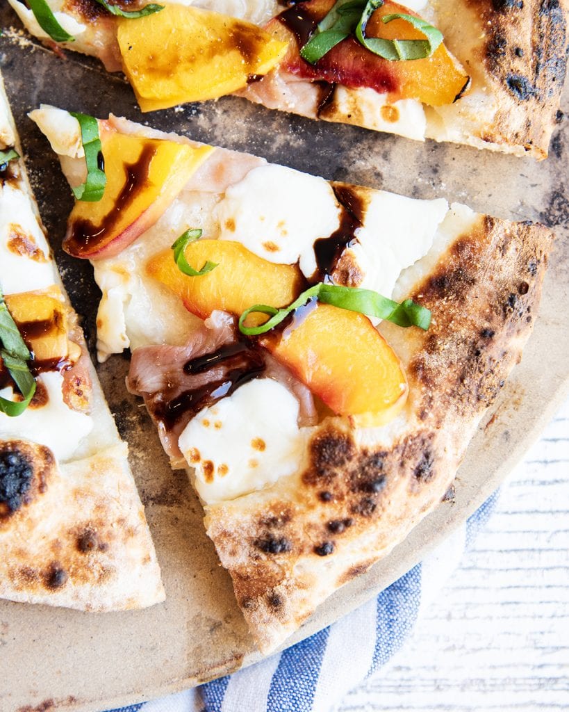 A slice of peach pizza with melted mozzarella cheese and a balsamic glaze on top.