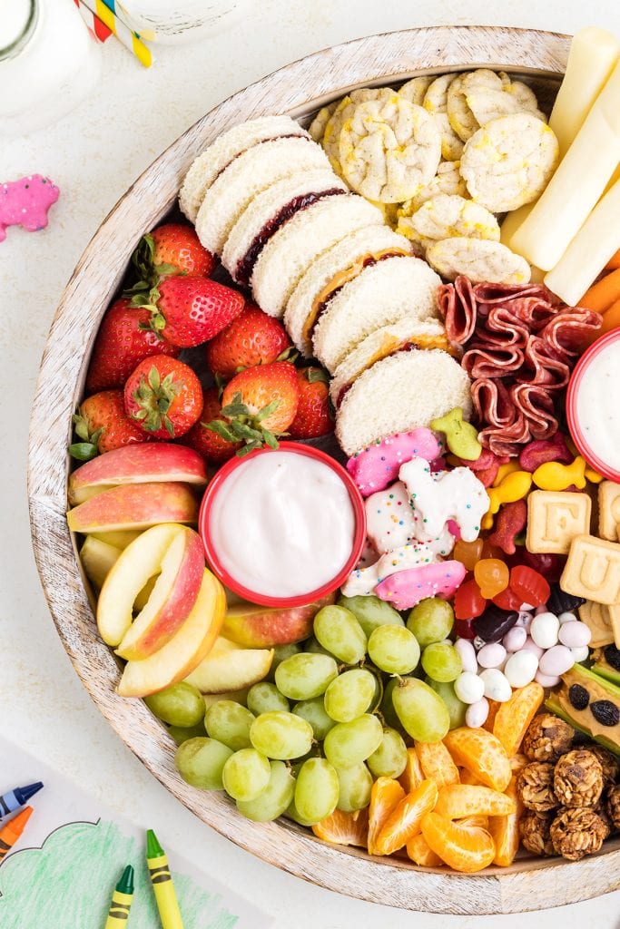 An overhead photo of a round wooden platter loaded with after school snack foods.