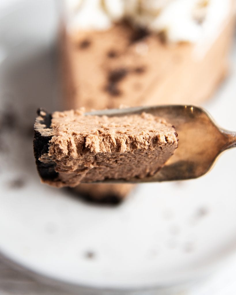 A bite of chocolate cheesecake on a fork.
