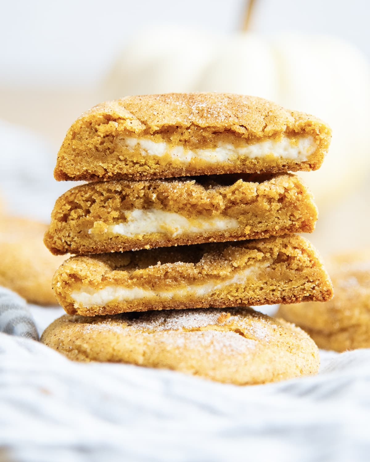 A stack of three halves of pumpkin cheesecake cookies, which are pumpkin snickerdoodle cookies with cheesecake filling in the middle.