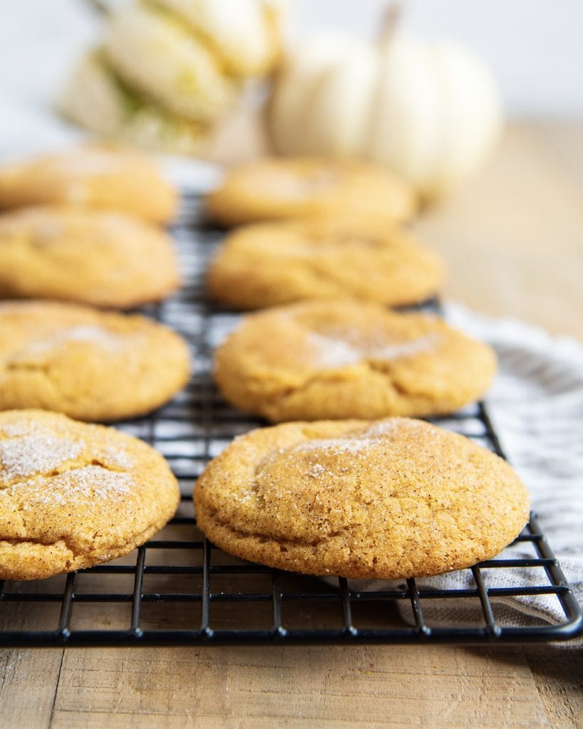 A wire rack with rows of pumpkin cookies.