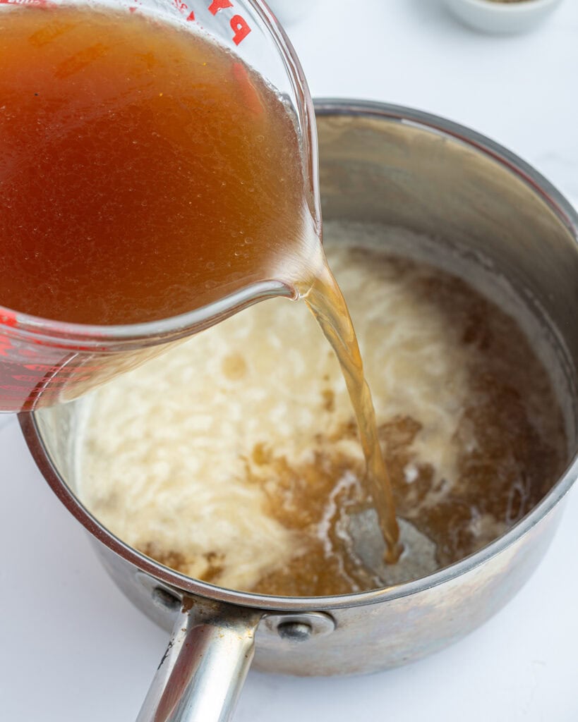 Turkey stock pouring into a pan.