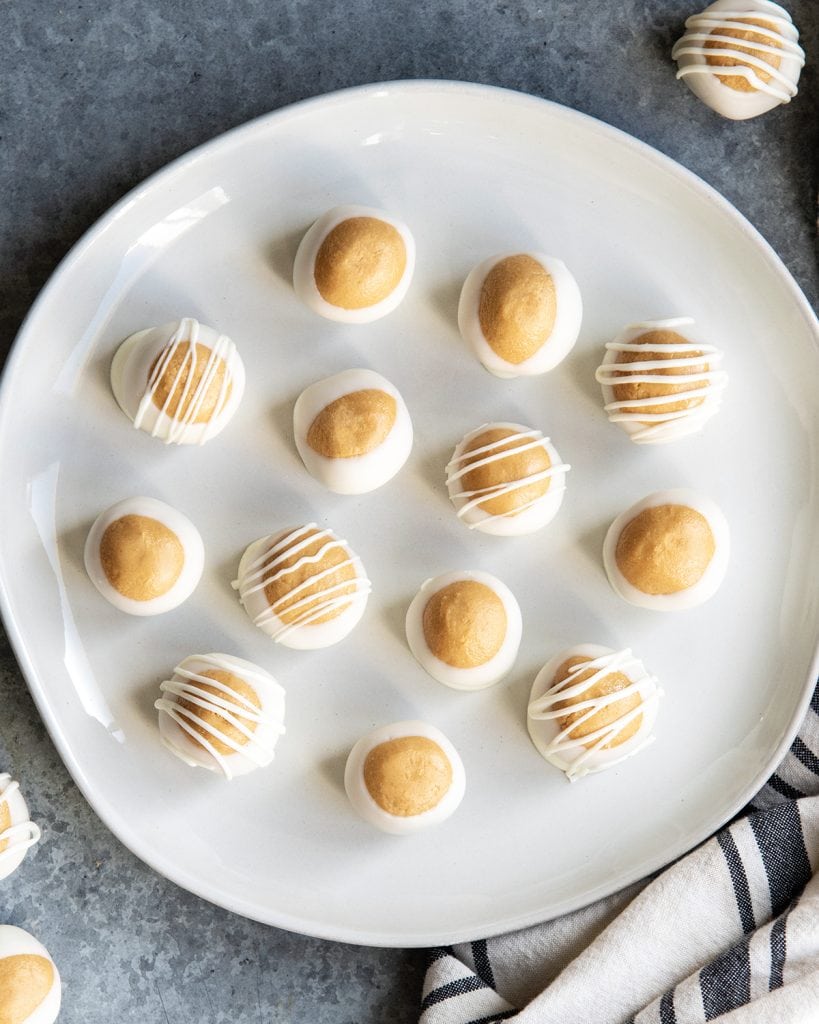 An overhead photo of a plate of Biscoff cookie butter buckeye balls dipped in white chocolate.