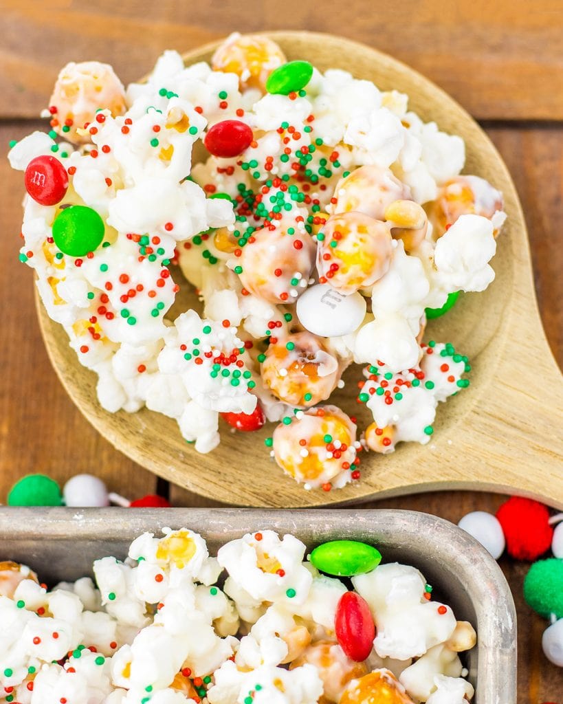 A wooden spoonful of white chocolate Christmas popcorn.