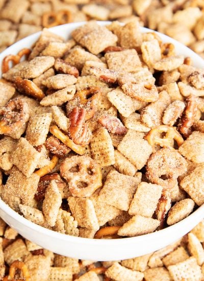A bowl of churro chex mix with mini pretzels and pecans.
