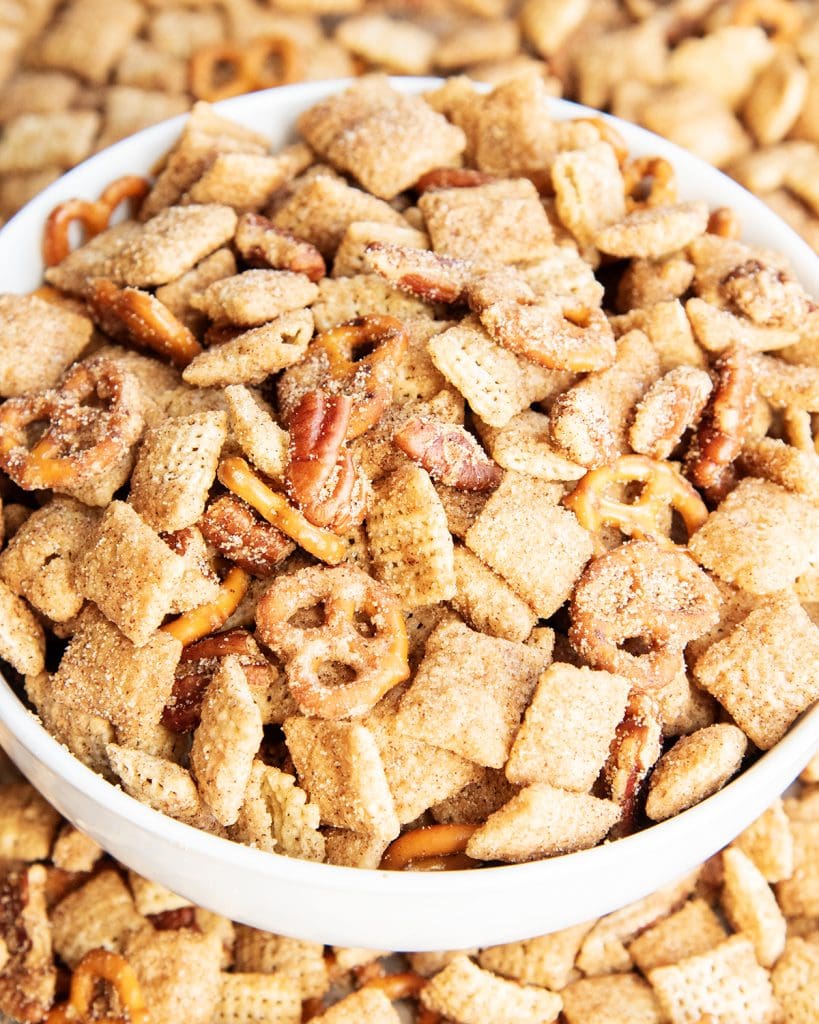 A bowl of churro chex mix with mini pretzels and pecans.