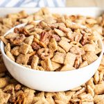 A bowl of cinnamon coated chex mix with pecans and mini pretzels too.