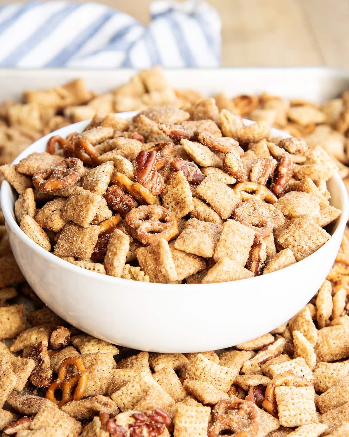 A bowl of cinnamon coated chex mix with pecans and mini pretzels too.