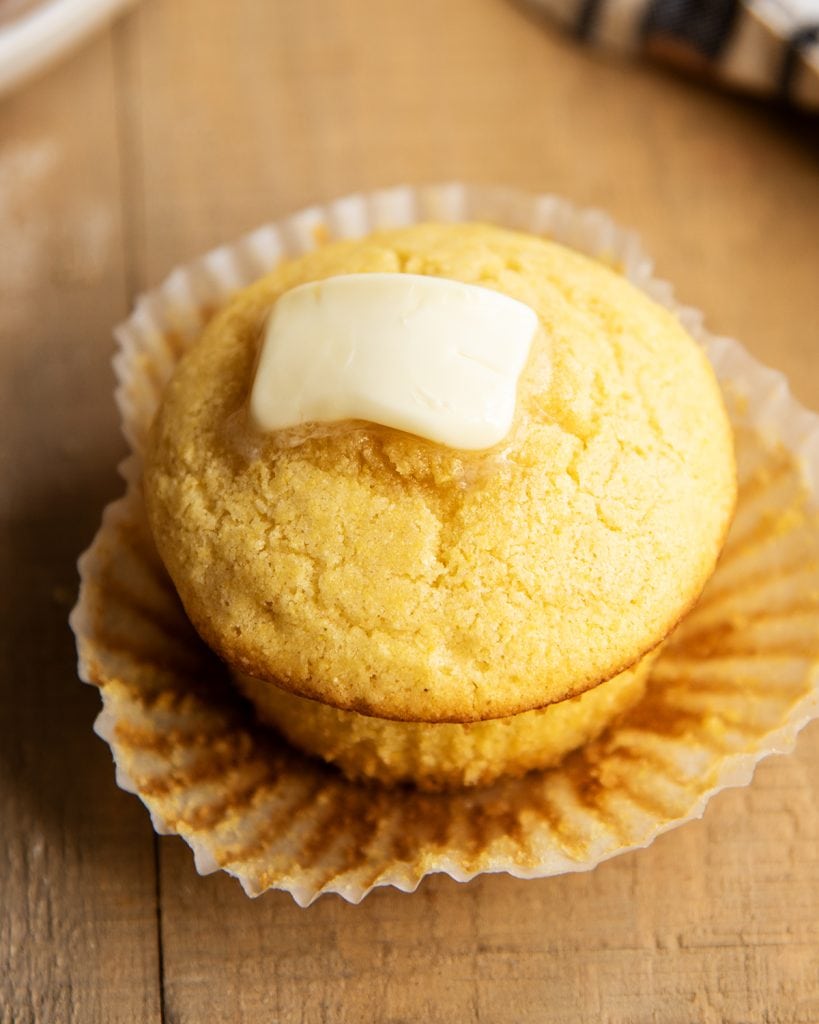 A cornbread muffin topped with a pat of butter.