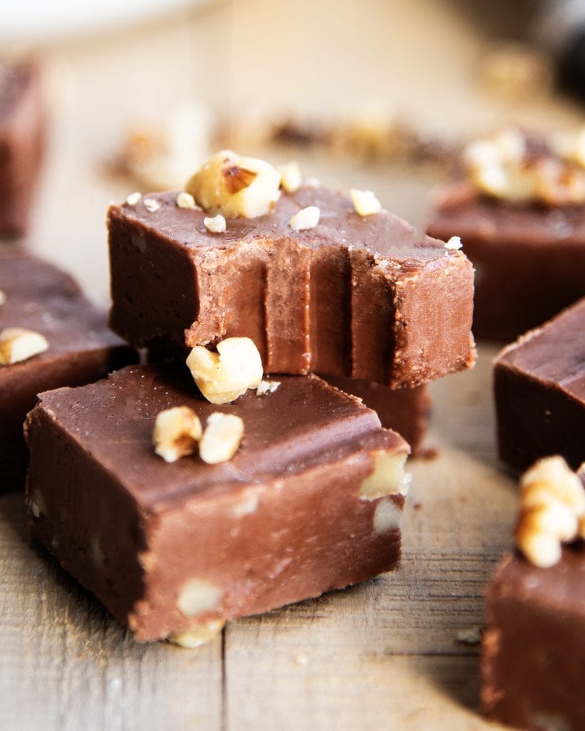 A piece of fudge with a bite out of it, topped with chopped walnuts.