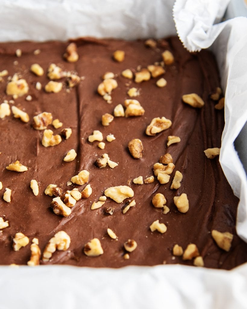 A pan of homemade fantasy fudge topped with chopped walnuts.