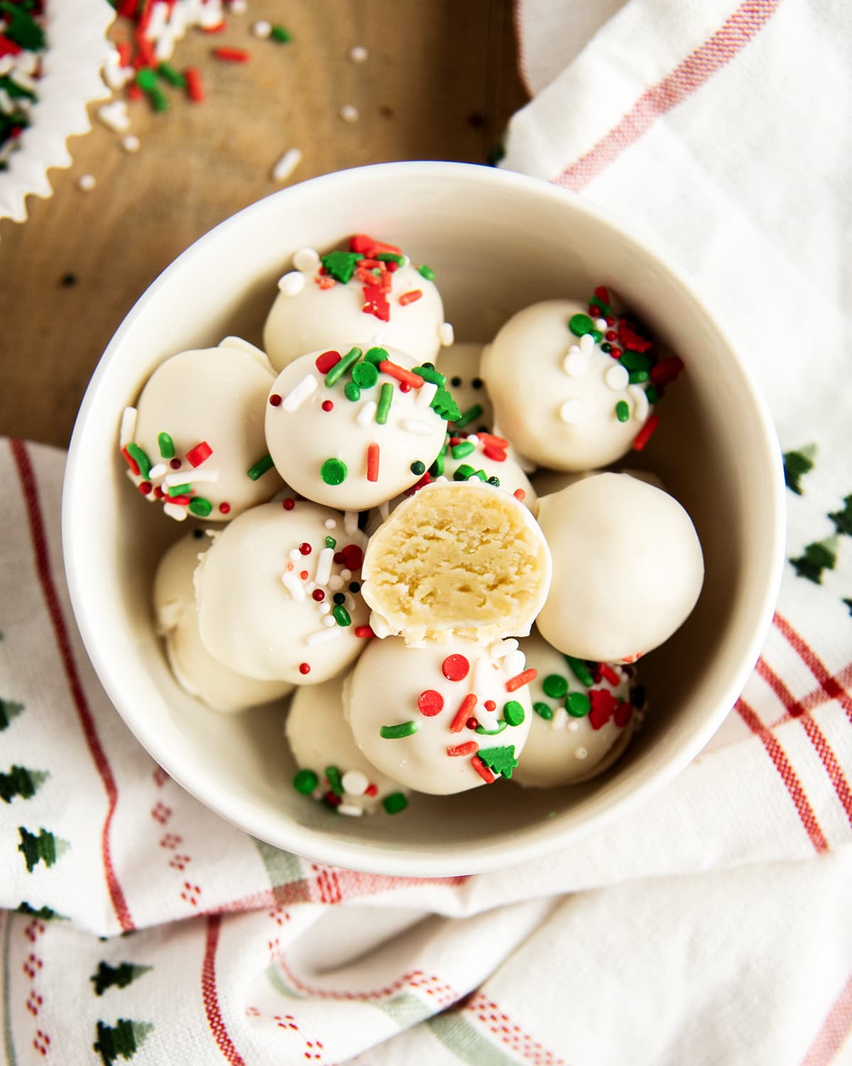 A bowl of sugar cookie truffles, one is cut in half showing the inside of the the truffle.