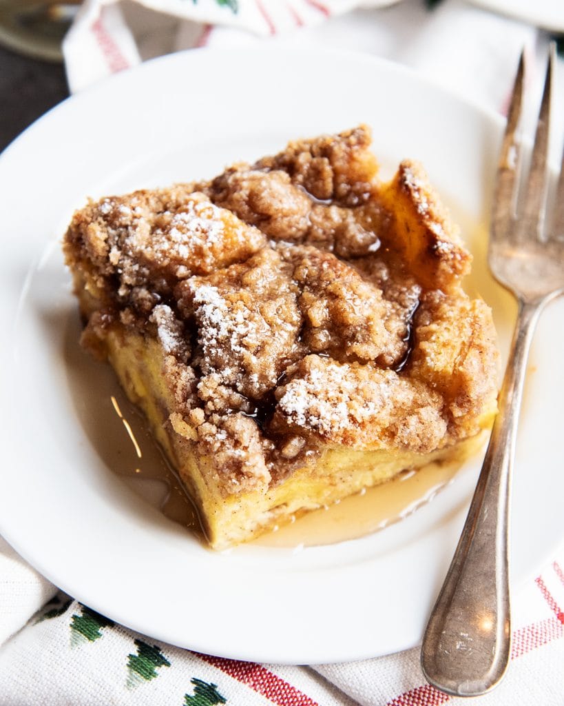 A plate of Eggnog French Toast Casserole on a plate topped with syrup.