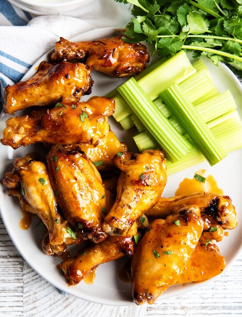 A plate of chicken wings and celery stick slices.