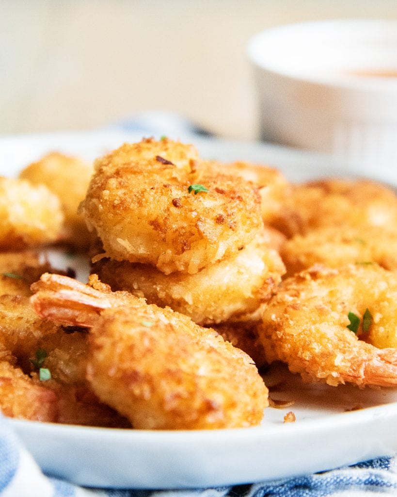 Golden brown coconut shrimp in a pile on a white plate.