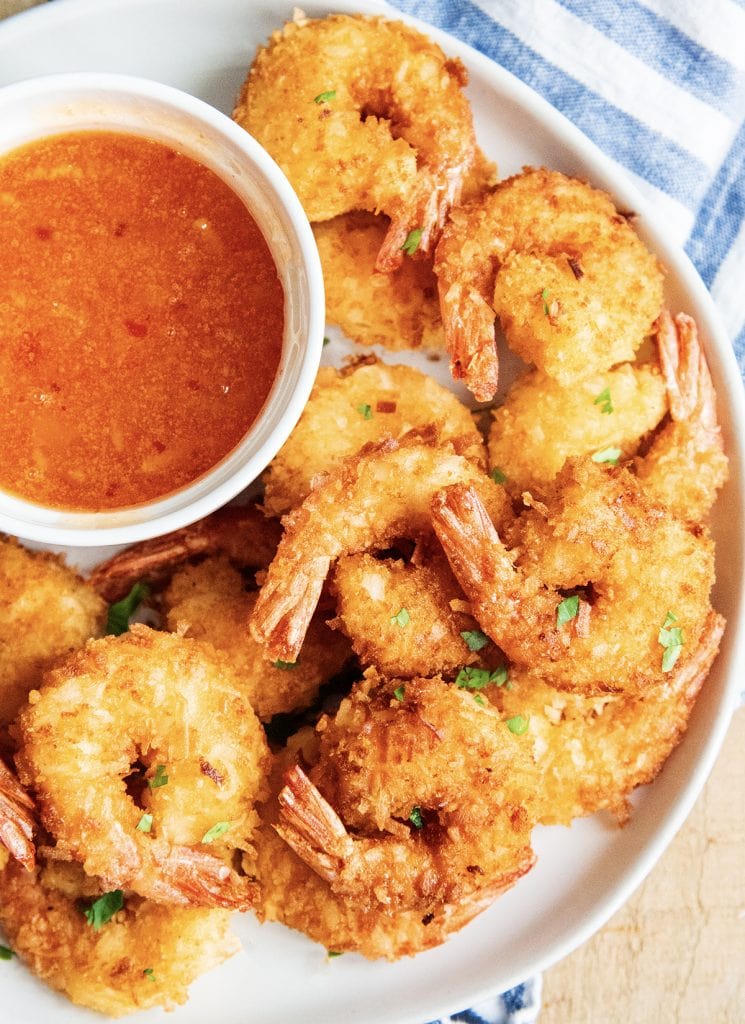 A plate of coconut shrimp with a bowl of thai chili sauce on it.