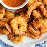 A pile of coconut shrimp topped with flakes of fresh cilantro.