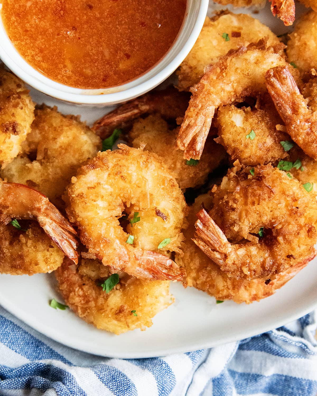 A pile of coconut shrimp topped with flakes of fresh cilantro.