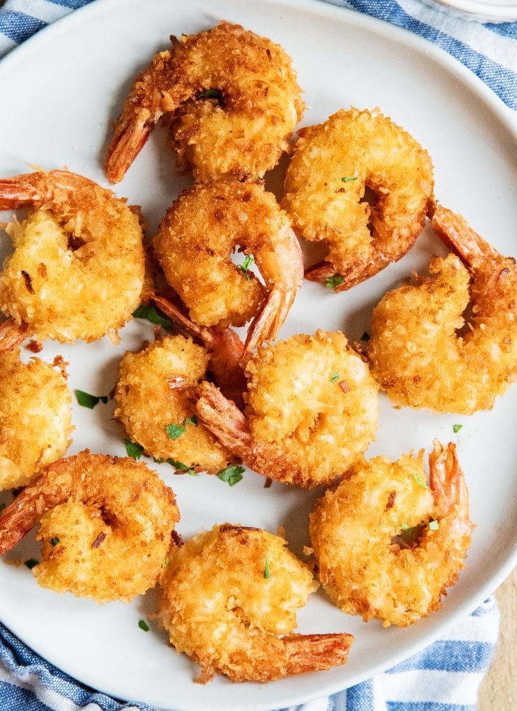A plate of coconut shrimp on a blue and white cloth.