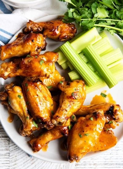 A plate of chicken wings and celery stick slices.