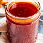 A glass jar full of homemade honey buffalo sauce with a text block over the top of the photo for pinterest.