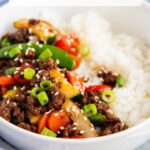 A photo of Korean beef with stir fried veggies in a bowl of white rice, with a text block over the top for pinterest.
