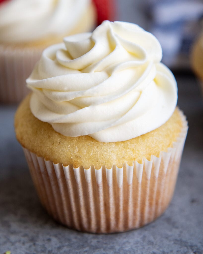 A vanilla cupcake topped with piped cream cheese whipping cream frosting.