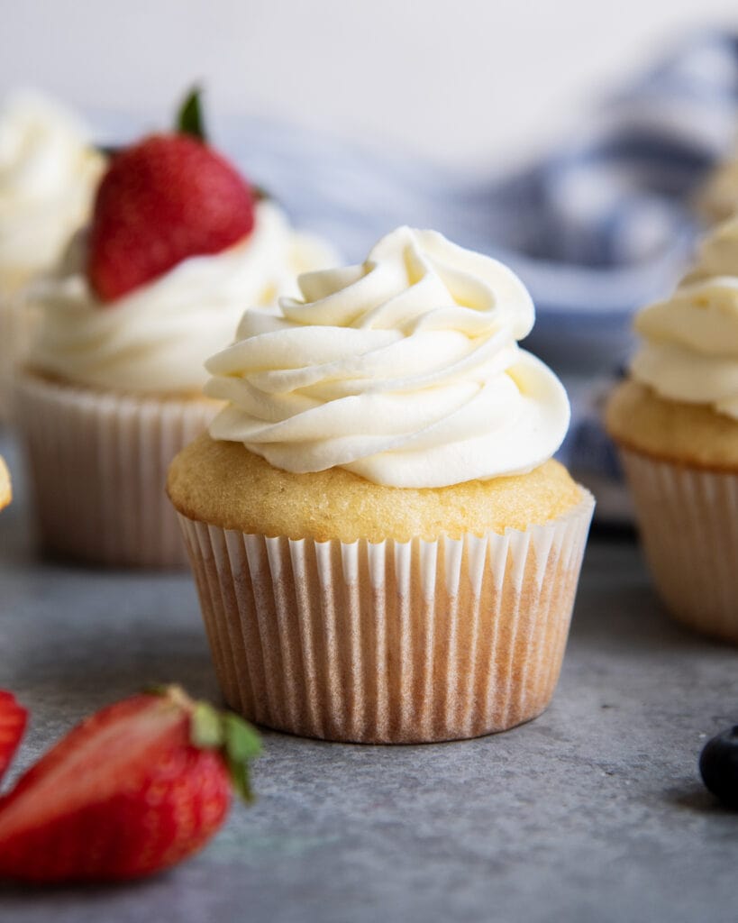 A yellow cupcake topped with whipped cream and cream cheese frosting.