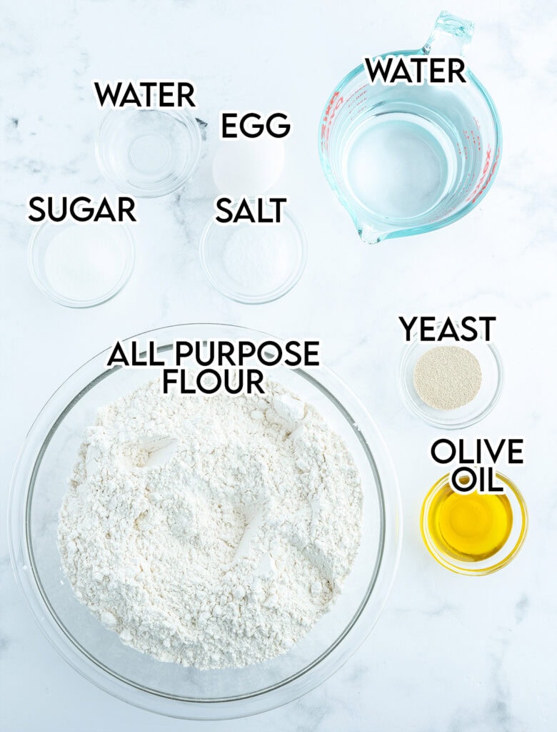 An above view of the ingredients needed to make french bread, all in bowls. 