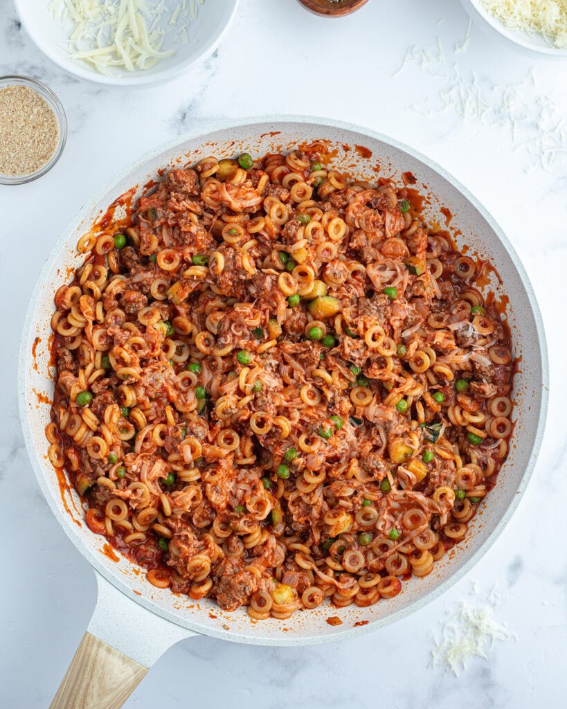 A saute pan full of pasta in a tomato sauce.