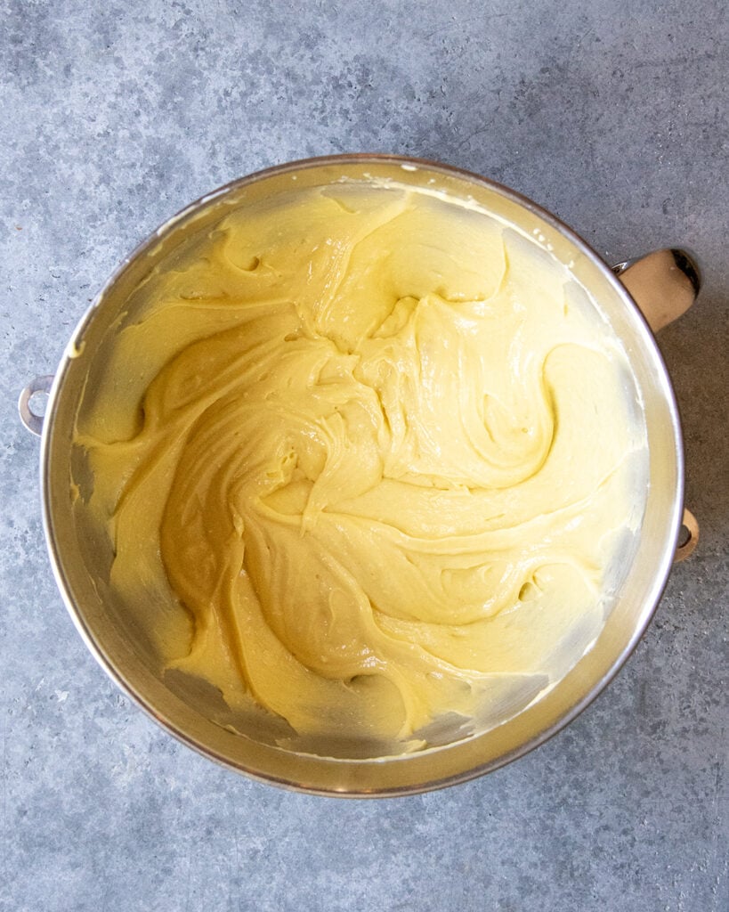 A mixing bowl full of a yellow cake batter. 