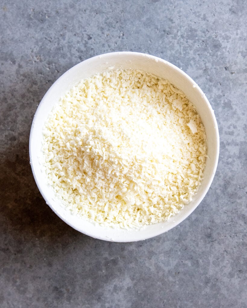 A white bowl full of grated white chocolate.