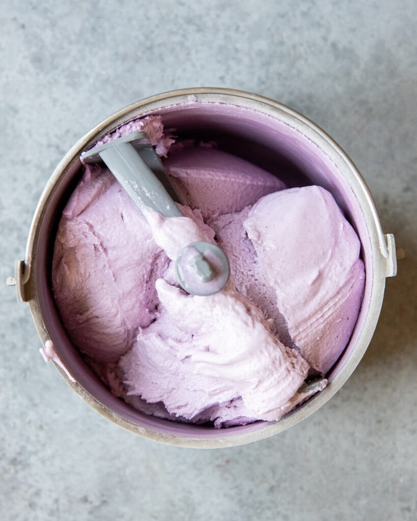 An ice cream maker full of purple colored blueberry ice cream.