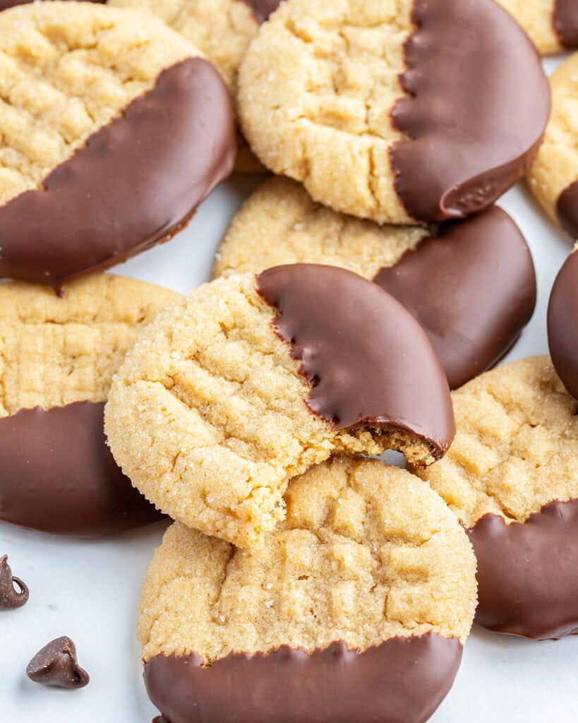 A close up of a peanut butter cookie with a forked pattern on top of it, and the cookie is dipped in chocolate with a bite out of it.
