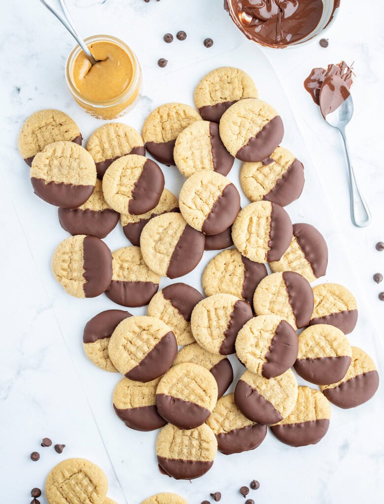 A pile of peanut butter cookies dipped half way in chocolate.