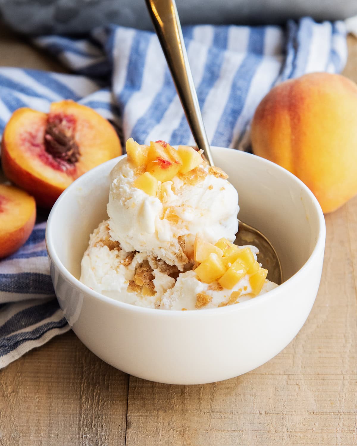 A bowl of peach pie ice cream topped with fresh peach pieces.