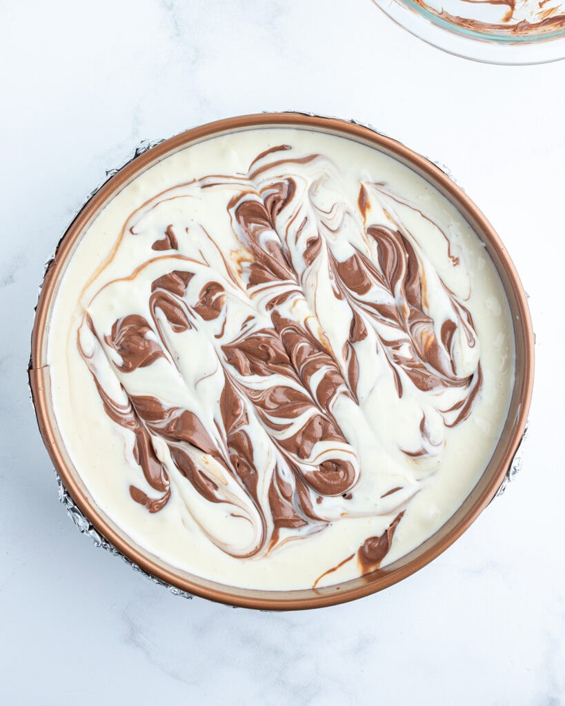 A marbled cheesecake batter in a spring form pan.