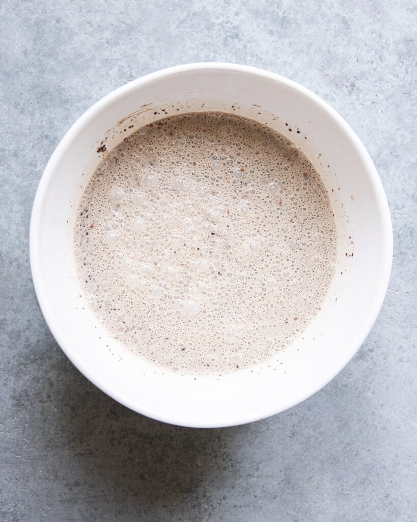 A bowl of a brown liquid mixture, that is a mocha ice cream base.