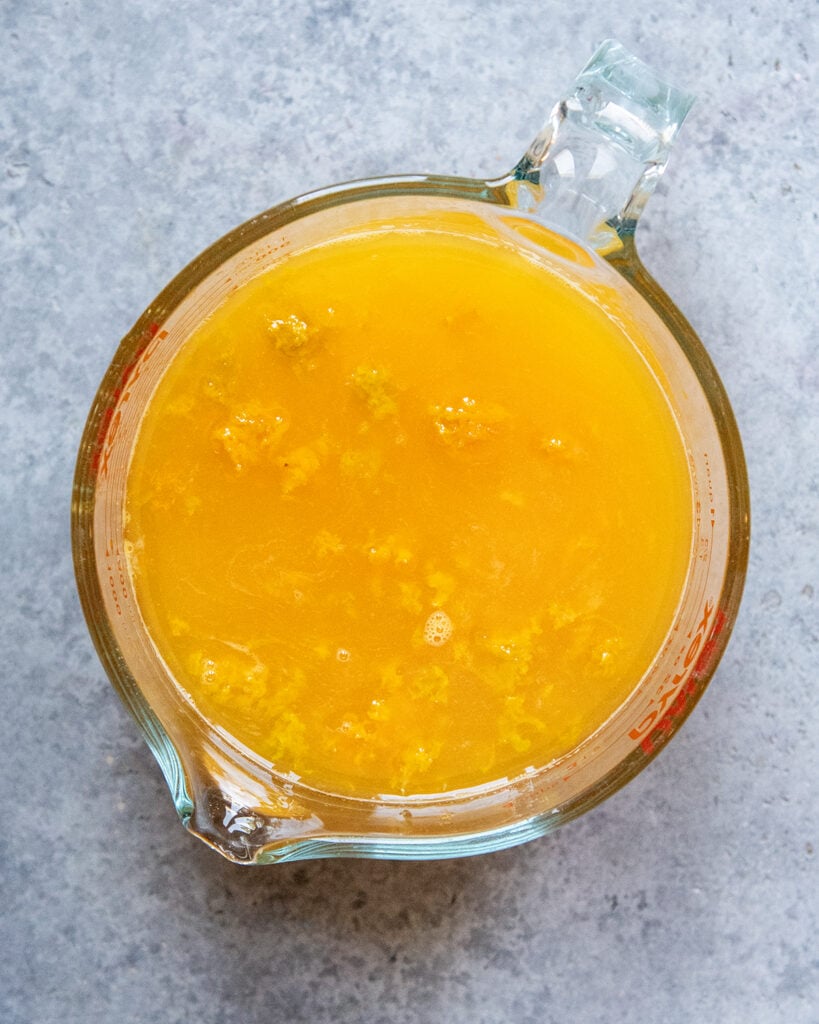 A bowl of the liquid ingredients to make orange sorbet, it looks like orange juice and orange zest.