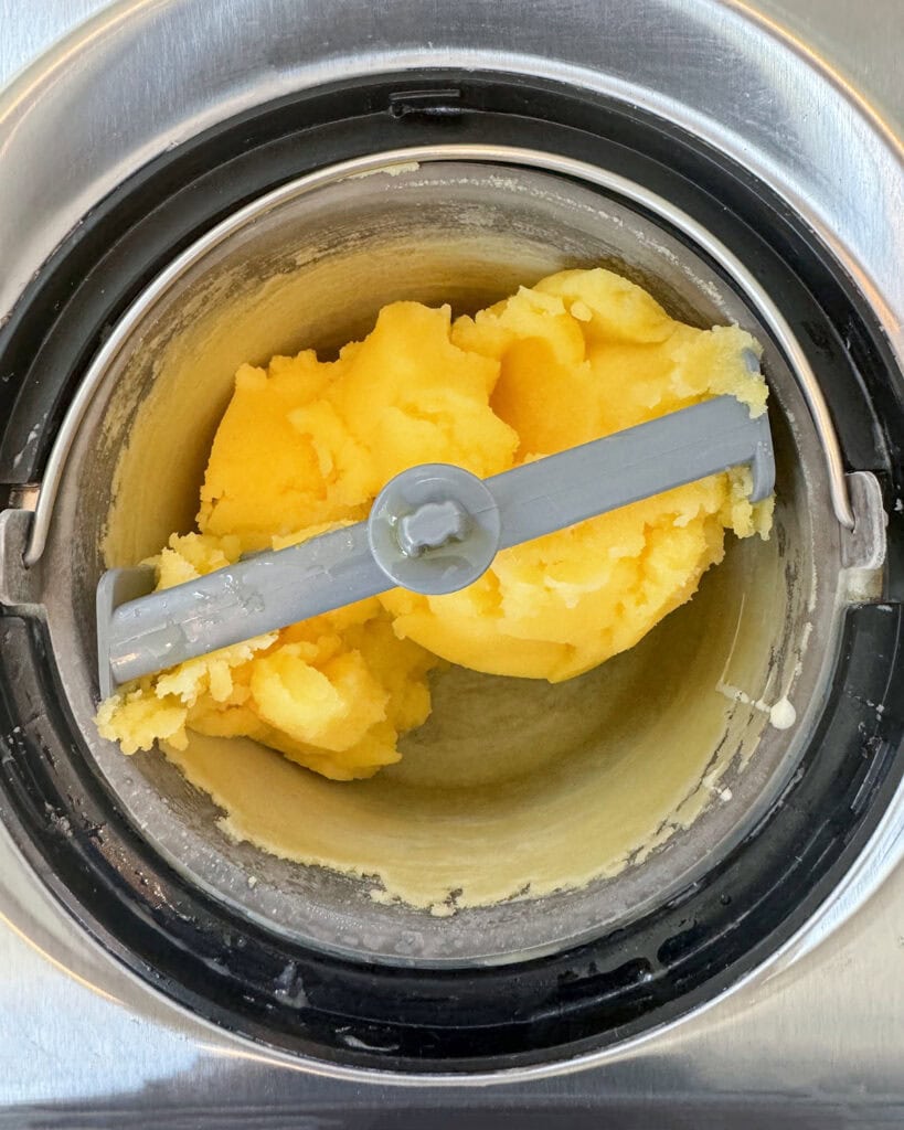 Churned orange sorbet in an ice cream maker.