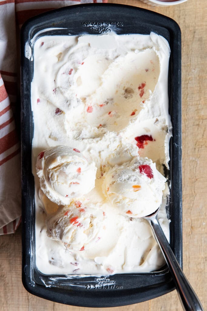 A bread pan full of frozen tutti frutti ice cream, with two scoops on top.