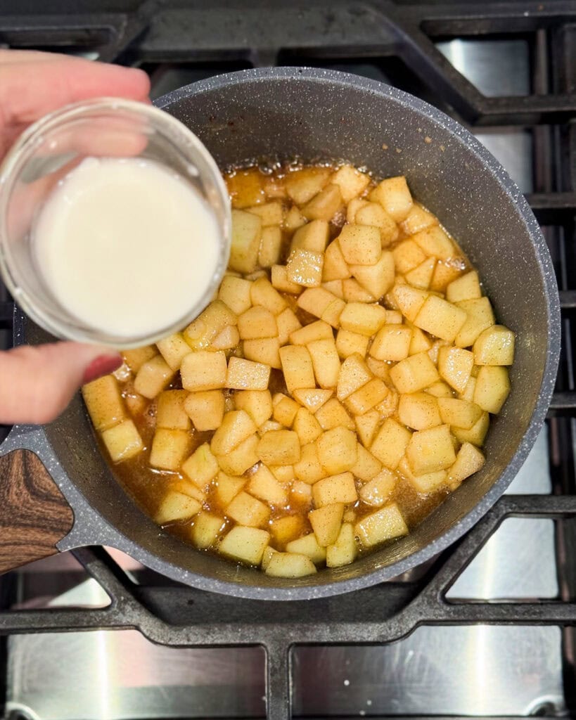 A bowl pouring cornstarch slurry over apple pieces.