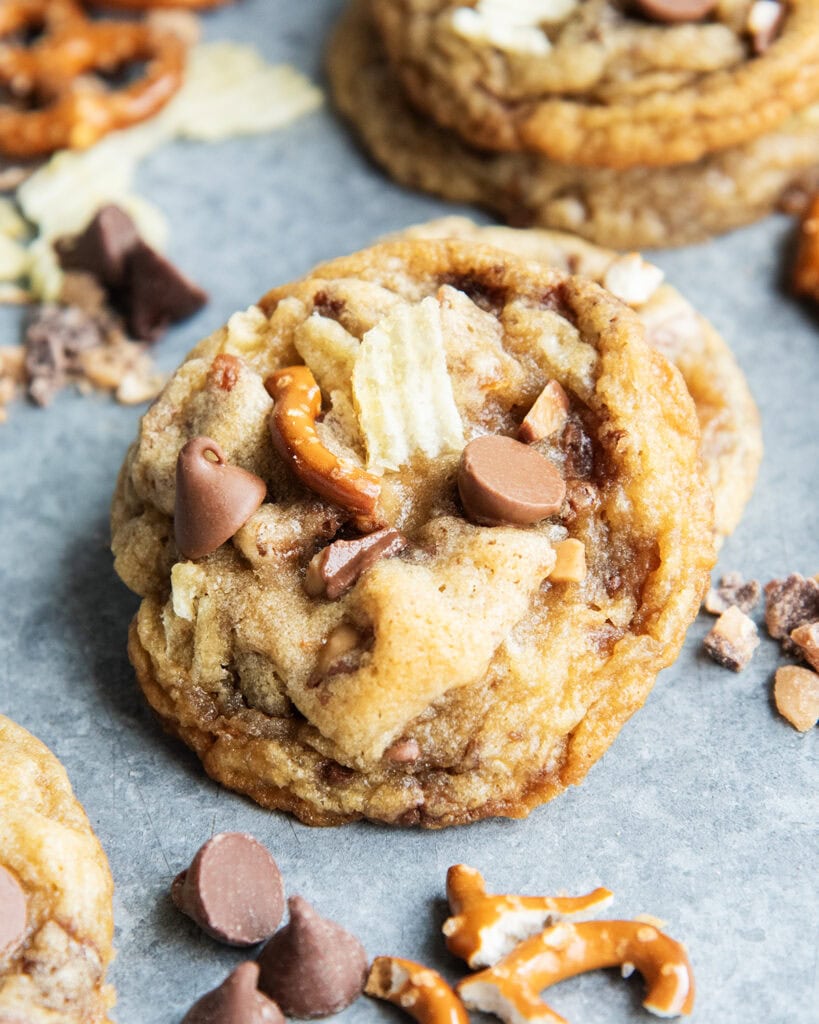 A pile of Kitchen Sink Cookies with chocolate chips, pretzel pieces, and chip pieces in it.