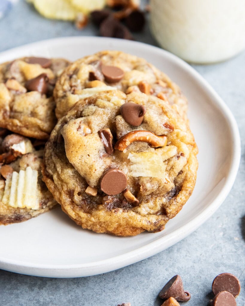 A pile of Kitchen Sink Cookies on a plate with chocolate chips, pretzel pieces, and chip pieces in it.