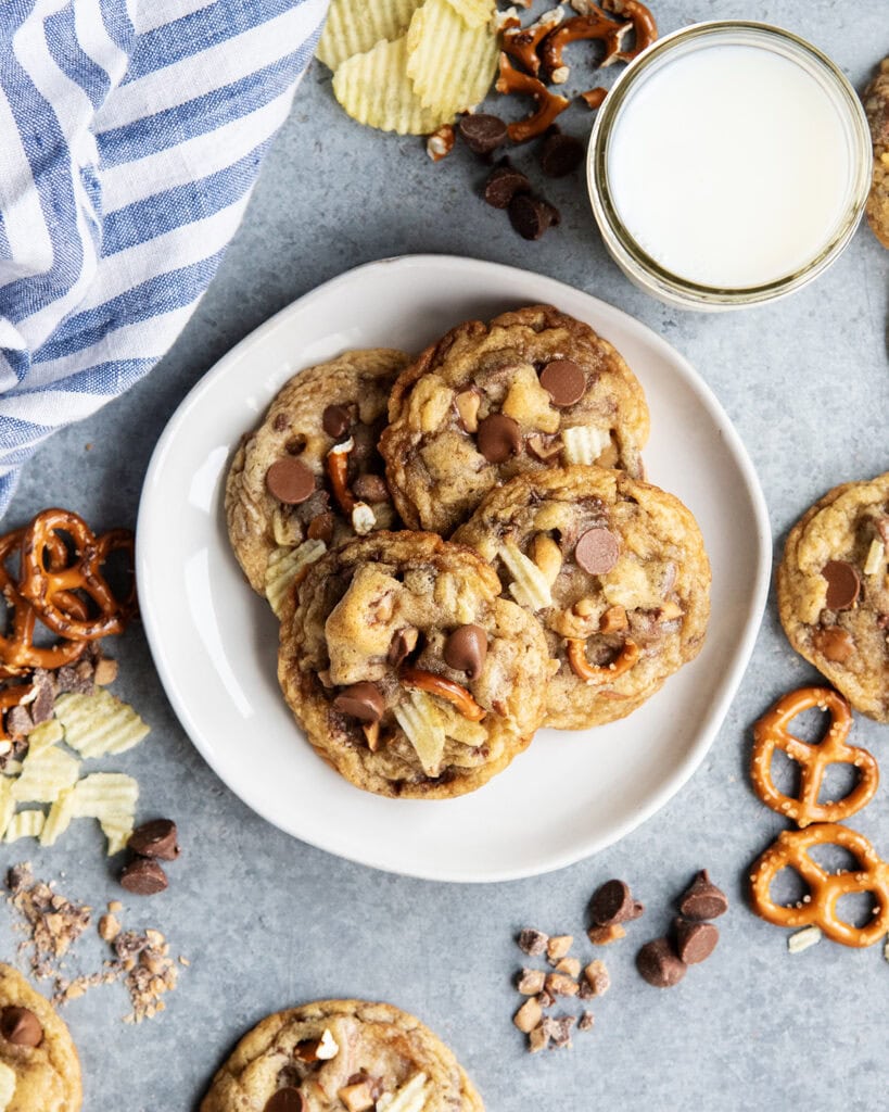 A pile of Kitchen Sink Cookies on a plate with chocolate chips, pretzel pieces, and chip pieces in it.