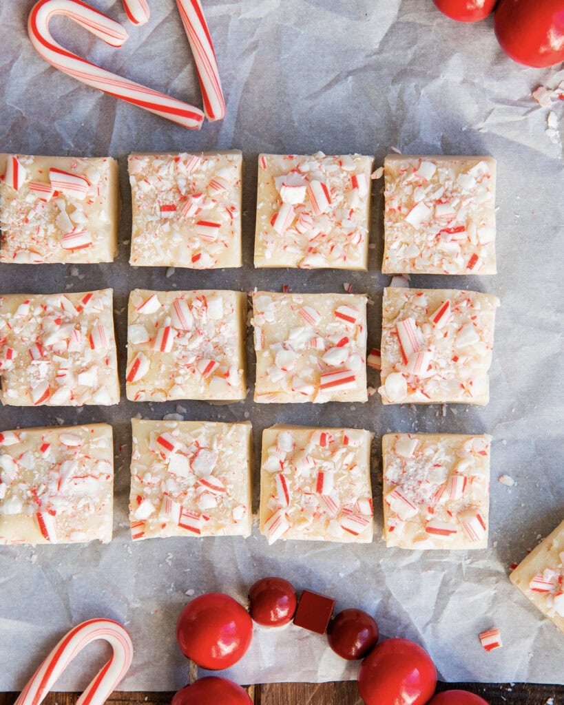 Rows of pieces of white chocolate fudge topped with candy cane pieces.