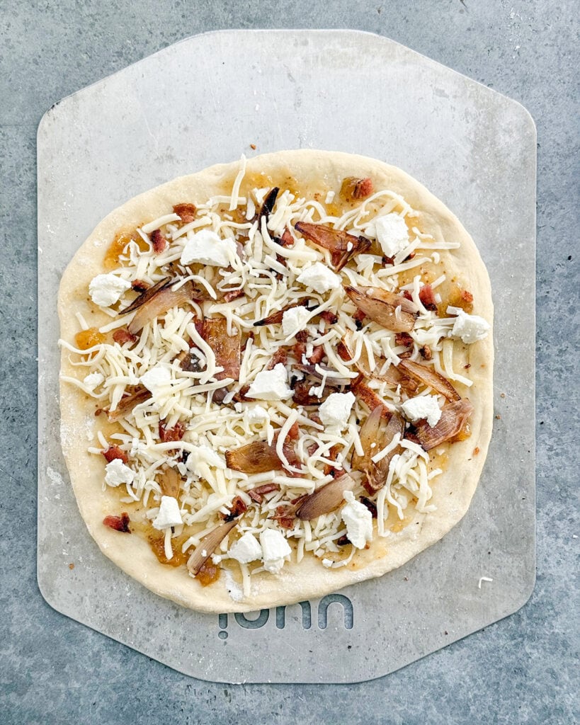 An uncooked pizza on a metal pan.