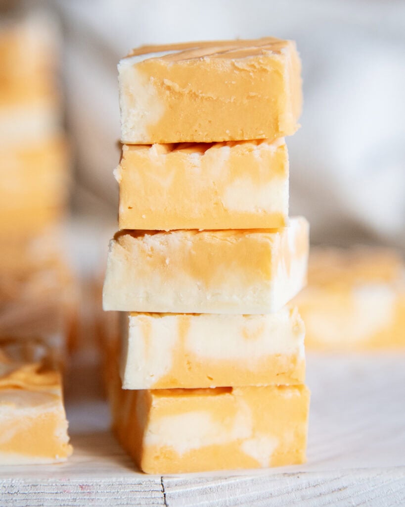 A stack of five pieces of fudge swirled with orange and white colors.